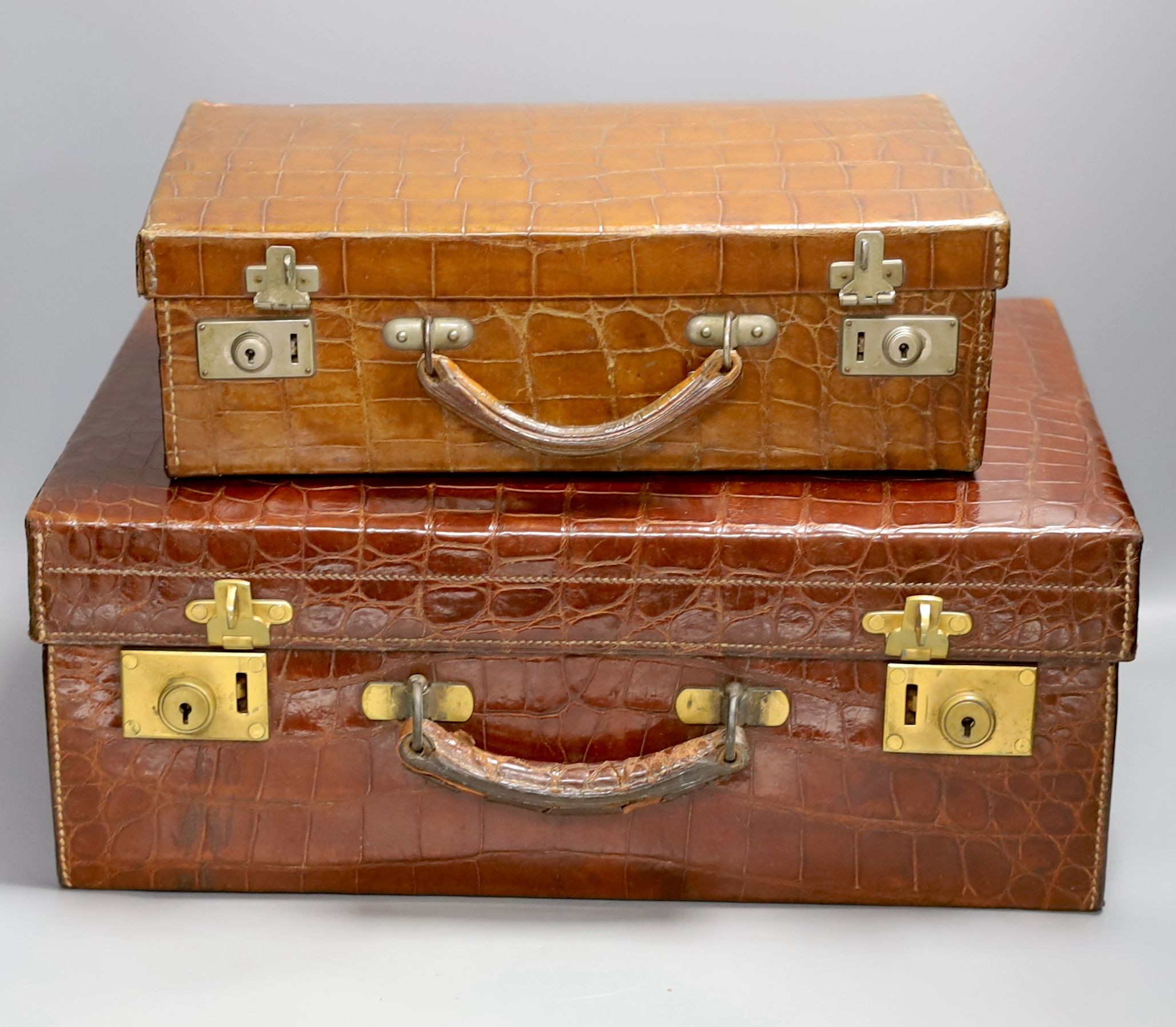 Two early 20th century crocodile hide suitcases, largest 48cms wide x 33 cms deep x 19cms high.